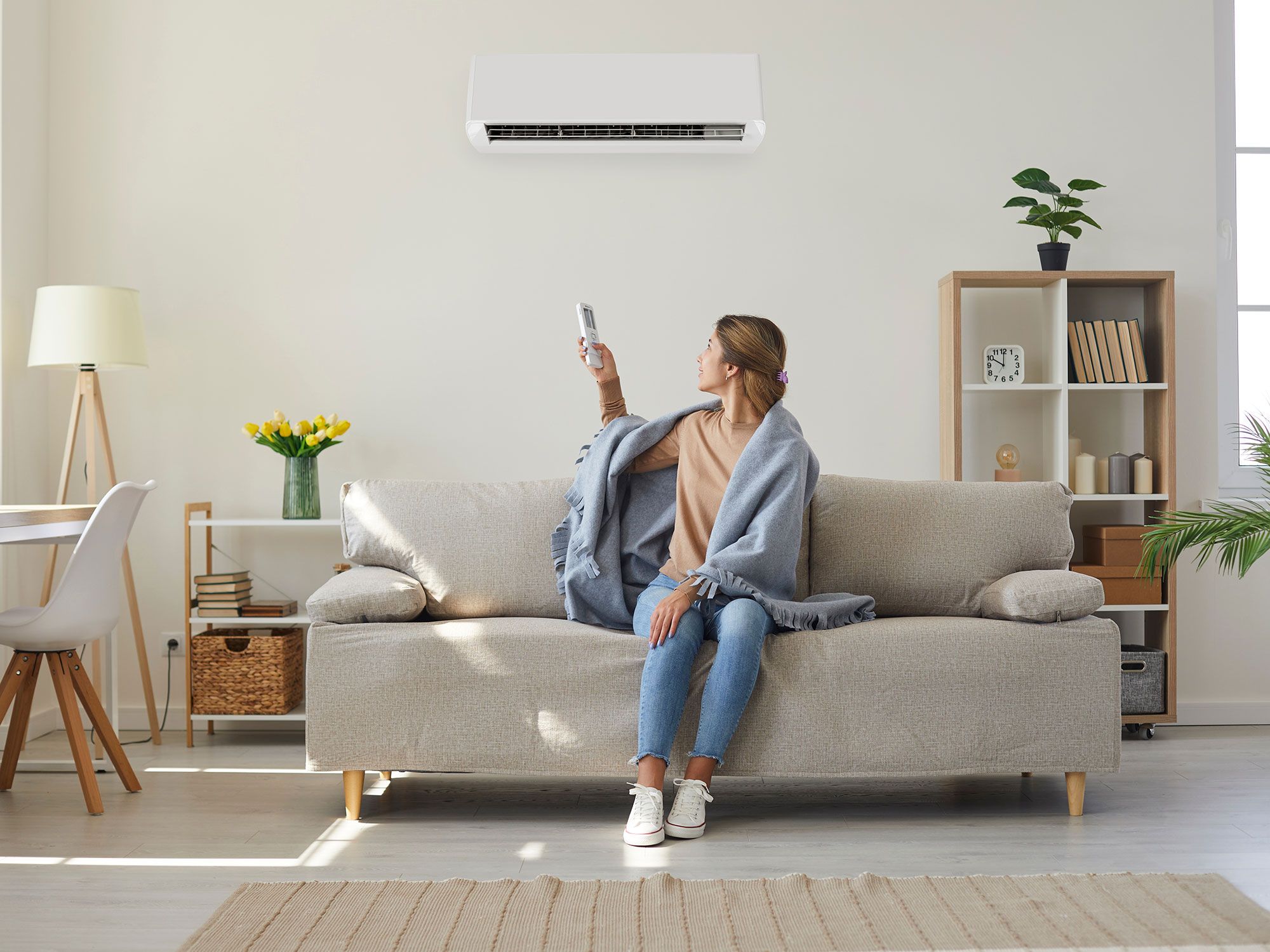 Eine Frau schaltet die Klimaanlage in ihrem Wohnzimmer ein
